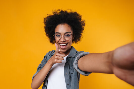 Joyful african american girl showing thumb up while taking selfie photo