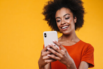 Joyful african american girl smiling while using mobile phone
