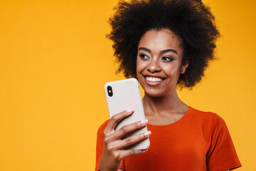 Joyful african american girl smiling while using mobile phone