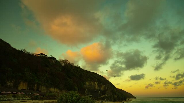 Paragliders fly during a beautiful sunset over the ocean and beach in Bali, Indonesia