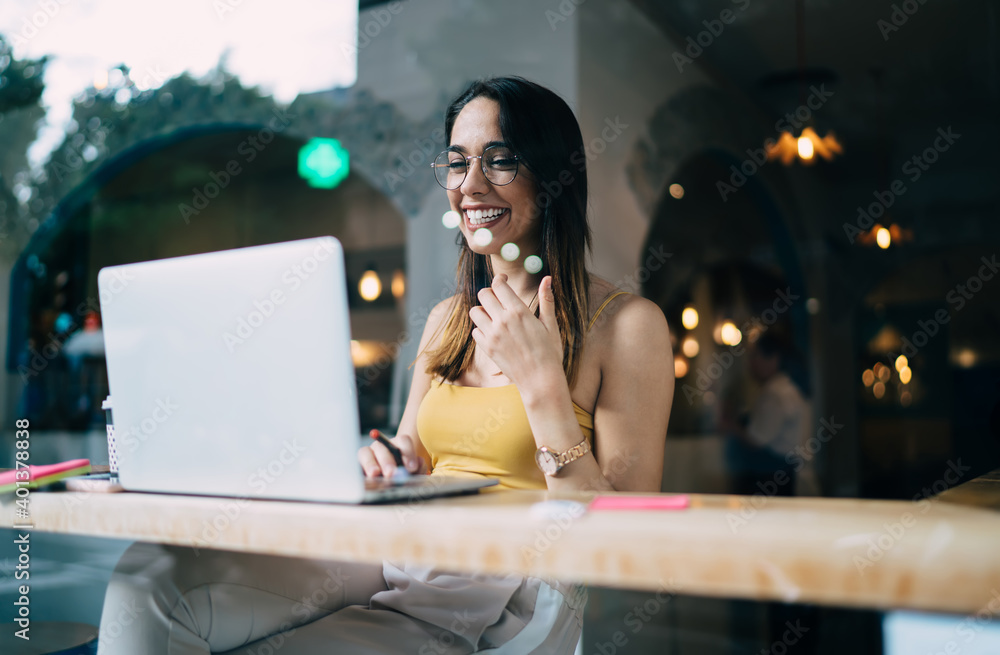 Poster cheerful hipster girl in spectacles reading received email news on modern netbook for networking soc