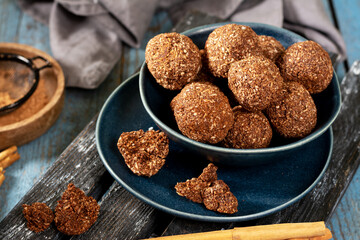 Chocolate coconuts. Chocolate balls with coconut. Chocolate candies or cookies with coconut, cinnamon and powdered sugar