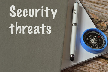 Selective focus with noise effect of pen, compass and notebook written with text SECURITY THREATS.