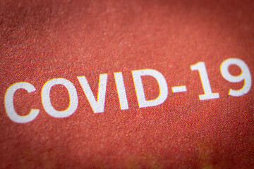 Fototapeta na wymiar Closeup COVID-19 roughly printed on a letter in dark and dangerous mood.