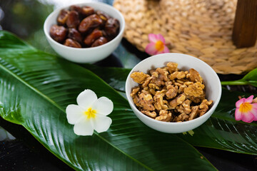 walnuts and dates decorated with tropical frangipani flowers in koh samui thailand, vegan and vegetarian healthy food