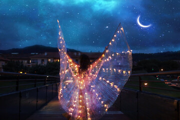 Belly dancer with wings of light under a starry sky