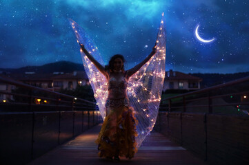Belly dancer with wings of light under a starry sky
