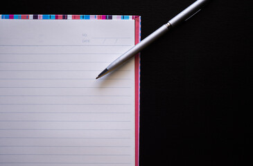Pen on book with wooden black background. flat lay with copy space. business and finance concept.