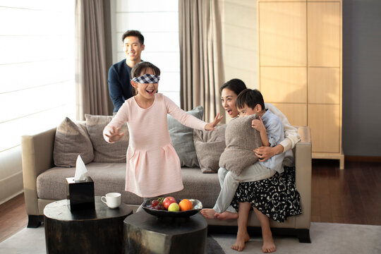 Happy young family playing hide and seek in living room