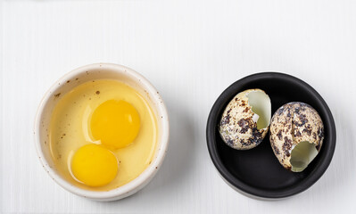 two yolks and two shells from quail eggs in different bowls on a light background. Cooking moment