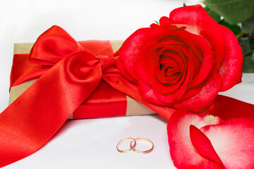Wedding rings and roses bouquet with gift and red ribbon