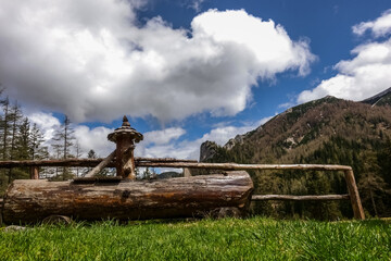 wooden fountain in the green nature with white clouds at the sky