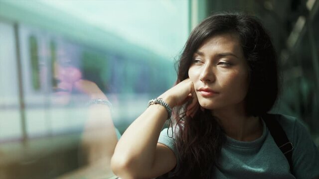 Teen girl looking at window of metro train. Cute asian woman travel by sky train in Thailand undeground. Concept of public transport and urban journey