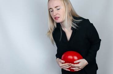 Bloating and flatulence concept. The woman holds a red balloon near the abdomen, which symbolizes bloating. Intestinal tract and digestive system. Problems with flatulence adn gastrointestinal tract