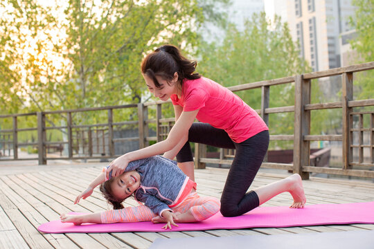 Happy mother and daughter doing yoga outdoors