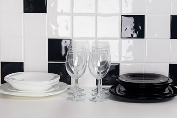 two sets of white and black utensils next to wine glasses on black and white background
