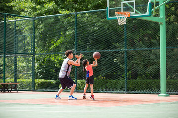 Happy father and daughter playing basketball on playground