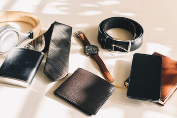 Top view male object, watch, flask, tie, belt, cell phone, wallet, notebook, headphones.