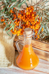 Fresh homemade sea buckthorn juice in a glass carafe and a branch of ripe orange vitamin useful...