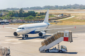 Mobile ladder and an arriving plane with passengers on the apron of the airfield.