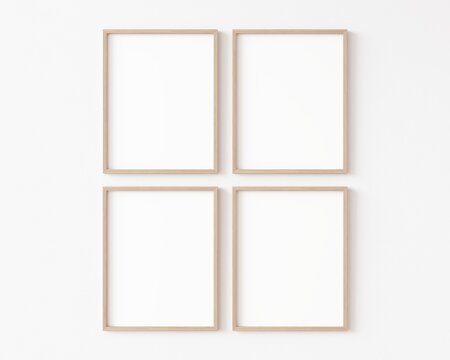 Four empty vertically oriented rectangular picture frames with thin wooden border hanging matrix-arranged on white wall. 3D illustration.