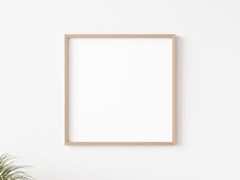 Blank square picture frame with thin wooden border hanging on white wall. 3D illustration.