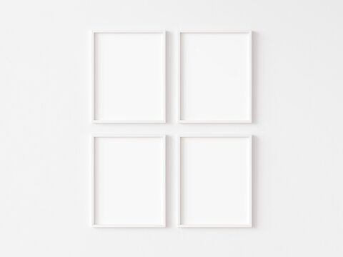 Four blank vertically oriented rectangular picture frames with thin white border hanging in two rows on white wall. 3D illustration.