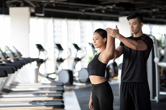 Young woman working out with personal trainer at gym