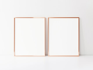 Two empty vertically oriented rosegold frames stand on the white table top. 3d Illustration.