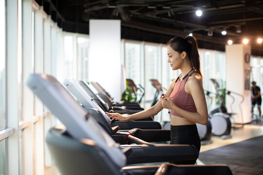 Young woman running on treadmill at gym