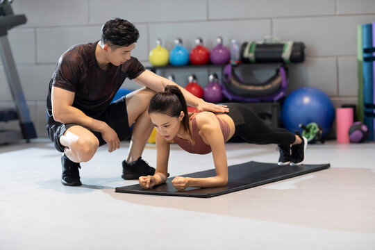 Young woman working out with personal trainer at gym