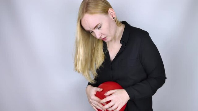 Bloating and flatulence concept. The woman holds a red balloon near the abdomen, which symbolizes bloating. Intestinal tract and digestive system. Problems with flatulence and gastrointestinal tract