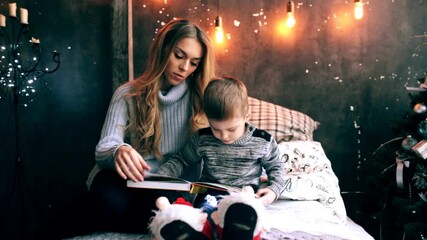 mother reading a book to her son in the bedroom on the bed