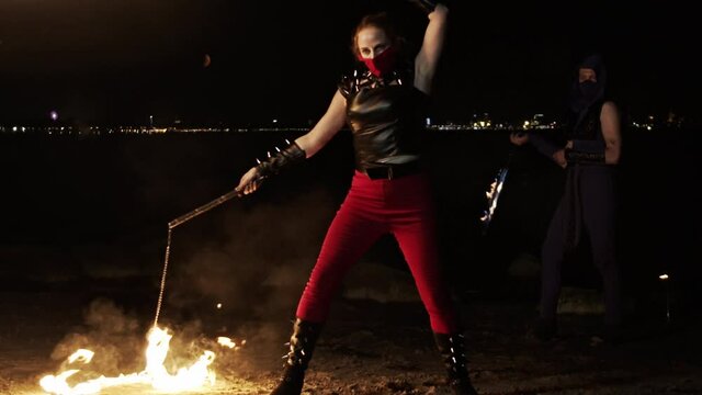 Wide shot of a female fire artist performing with fire whips