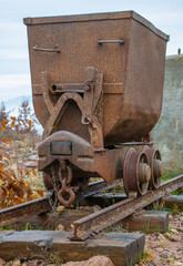 Fototapeta na wymiar Old rusty mining cart on a rail track . Decoration in the park.
