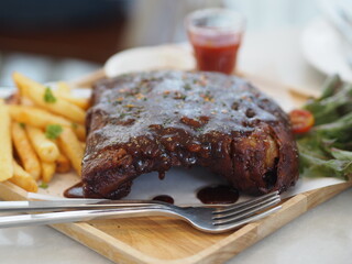 Pork Spareribs BBQ, Barbeque Pork Ribs with french fries vegetable salad, tomato sauce in a clear glass on wooden tray, food