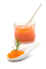 Closeup of trout roe in a ceramic spoon with a dill leaf with a transparent glass container on white background