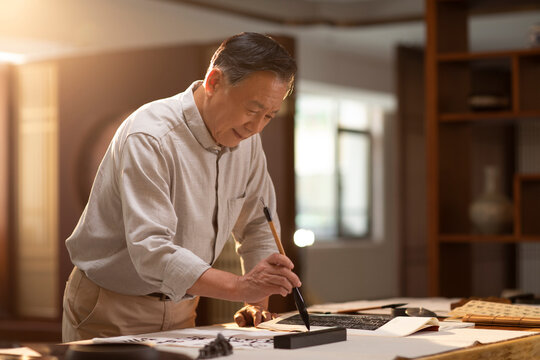 Senior man practicing calligraphy in the study
