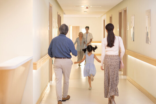 Little girl running to embrace grandmother in hospital corridor - Powered by Adobe