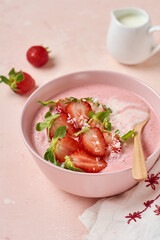 Breakfast with granola, coconut and strawberry smoothie in a bowl on a pink light background. Top view.