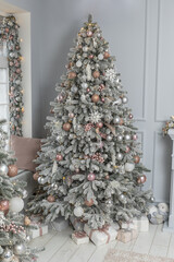 Beautiful holdiay decorated room with Christmas tree with presents under it. Stylish Christmas interior decorated in gray colors. Comfort home.