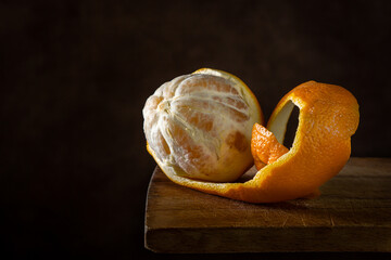 Orange on a wooden surface. Citrus fruit. Half peeled orange