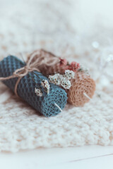 Close up of two colored natural decorative  beewax candles with dried flowers and a honey aroma for interior and tradition on a white knitted sweater. A delicate color palette. Handmade