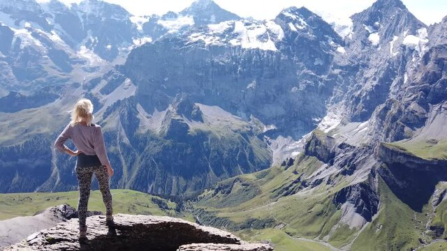 Tourist woman relaxing after hiking at Schilthorn viewpoint in Bernese Oberland, Jungfrau Region. Mountain panorama of the Eiger, Monch and Jungfrau UNESCO World Heritage Site and over 200 peaks.