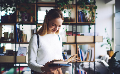 Happy teen standing in bookstore with open book