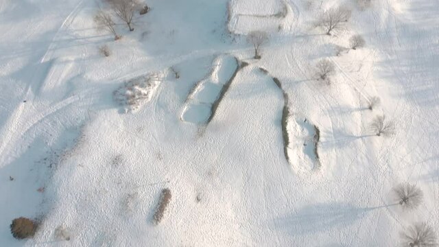 Drone pull back and pan downward to show the snow-covered country club, tees, and other features of the post-blizzard golf course. Ends short of birds-eye.