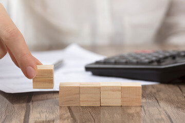 Female hand arranging wood block stacking as step stair. Ladder career path concept for business growth success process
