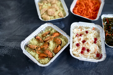 Different foil containers with delicious food. Delivery service