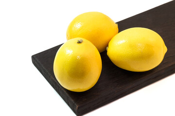 Fresh lemons on a kitchen cutting black wooden board, isolate on a white background.