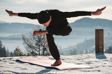 Caucasian senior man doing yoga exercises in front of amazing sunset on the winter mountains. Copy,...